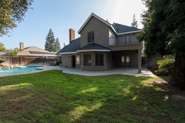 back of property featuring a yard, a balcony, a fenced in pool, and a patio area