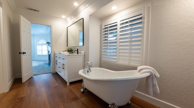 bathroom featuring crown molding, wood-type flooring, a bathtub, and vanity