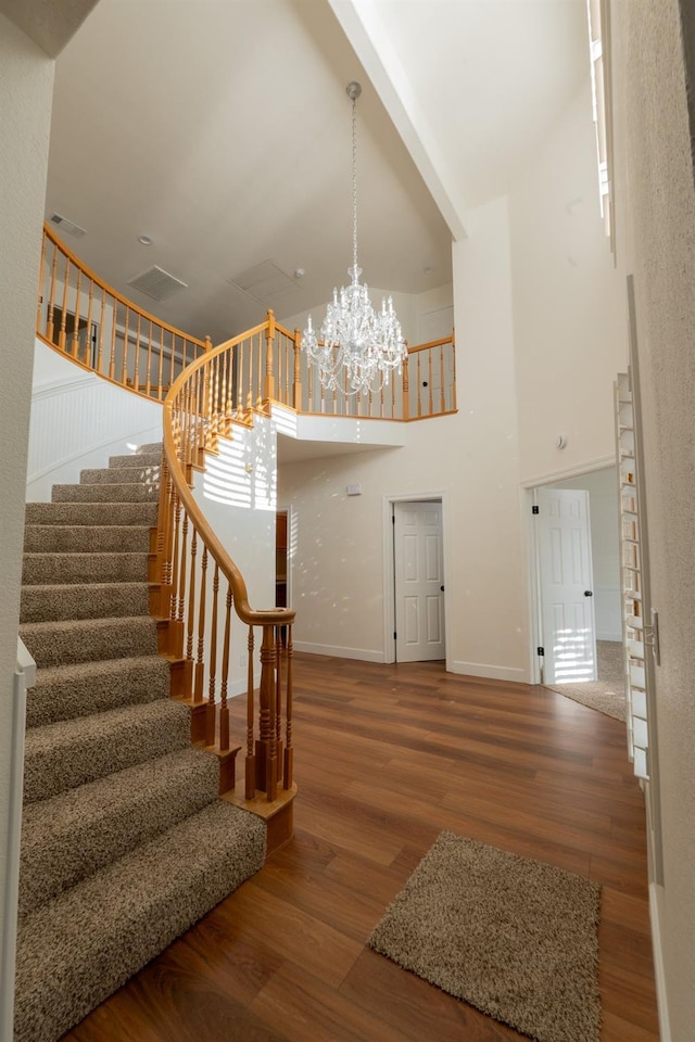 stairs featuring hardwood / wood-style floors, a notable chandelier, and a towering ceiling