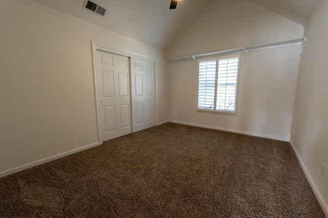 unfurnished bedroom featuring a closet, vaulted ceiling, dark carpet, and ceiling fan