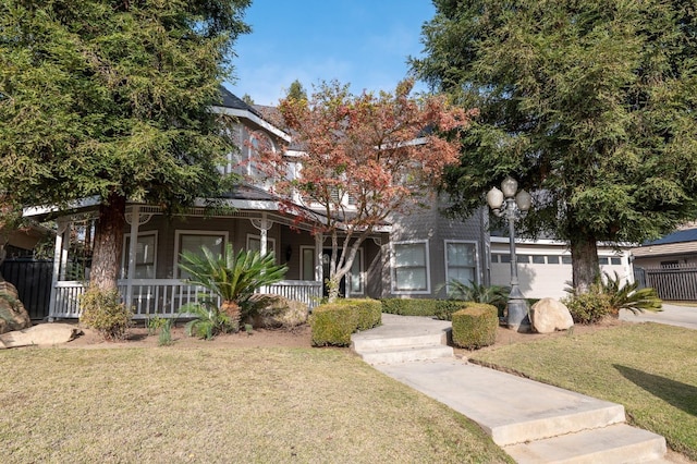 view of property hidden behind natural elements with covered porch, a garage, and a front yard