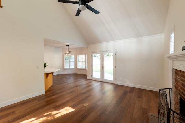 unfurnished living room with french doors, ceiling fan with notable chandelier, dark hardwood / wood-style flooring, a fireplace, and high vaulted ceiling