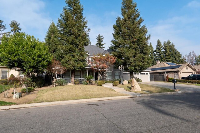 view of property hidden behind natural elements with a garage and a front lawn