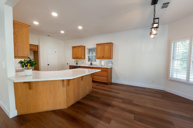 kitchen featuring sink, a kitchen breakfast bar, crown molding, dark wood-type flooring, and kitchen peninsula