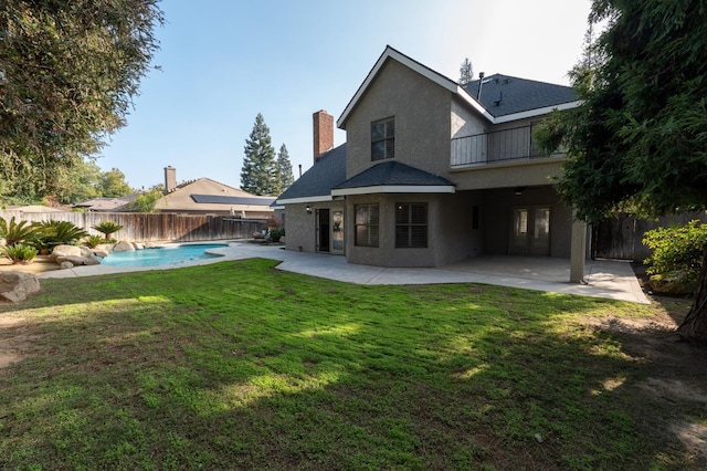 back of house featuring a fenced in pool, pool water feature, a patio area, and a balcony