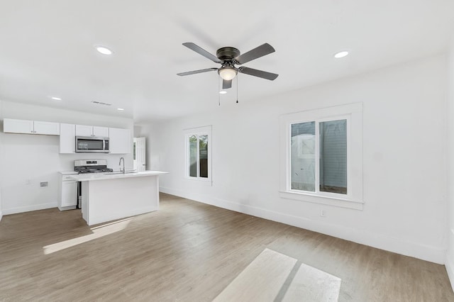 unfurnished living room featuring ceiling fan, sink, and light wood-type flooring