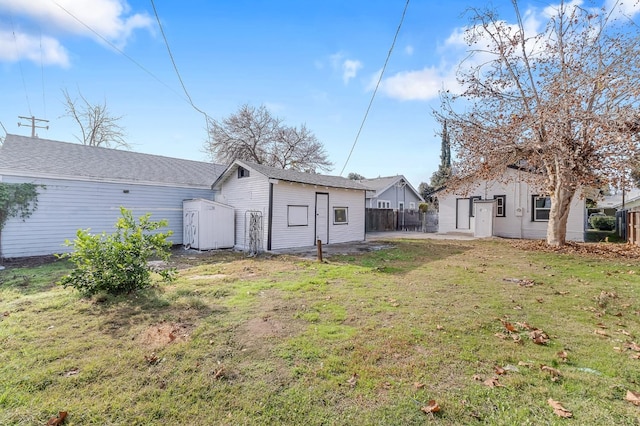 back of house featuring a lawn and a storage unit