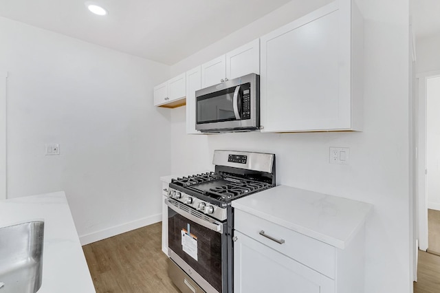 kitchen featuring sink, white cabinets, light wood-type flooring, and appliances with stainless steel finishes