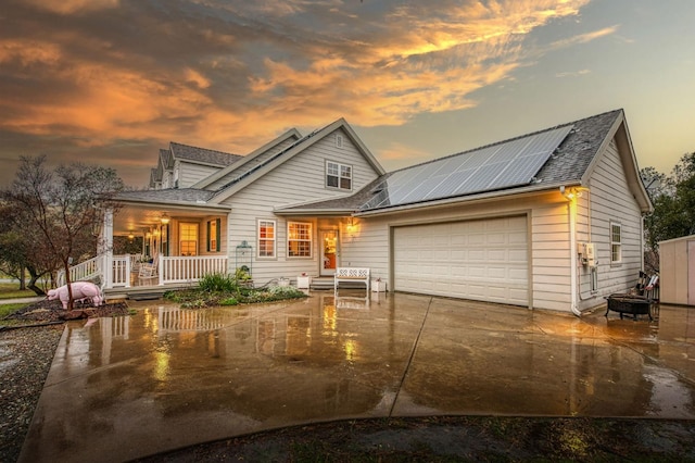 view of front of house featuring a garage, a porch, and solar panels