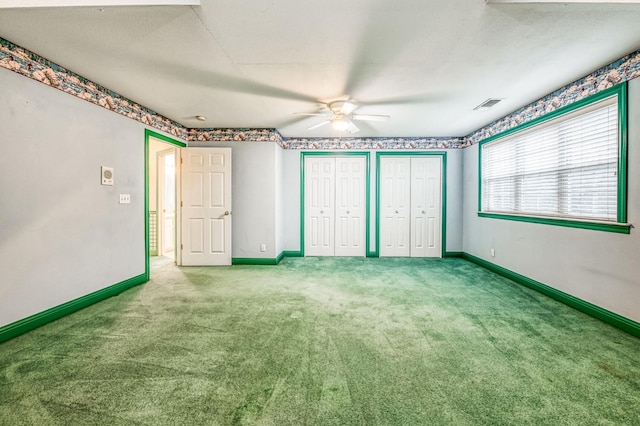 unfurnished bedroom with ceiling fan, light colored carpet, a textured ceiling, and two closets