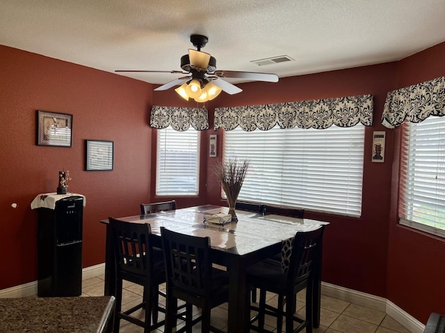 tiled dining area with a textured ceiling and ceiling fan