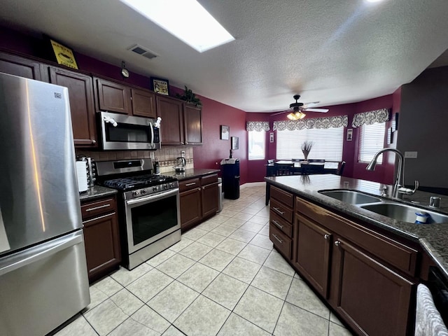 kitchen with ceiling fan, sink, stainless steel appliances, a textured ceiling, and light tile patterned flooring