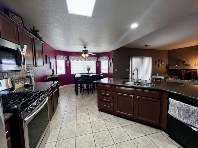 kitchen with appliances with stainless steel finishes, dark brown cabinets, ceiling fan, sink, and light tile patterned flooring