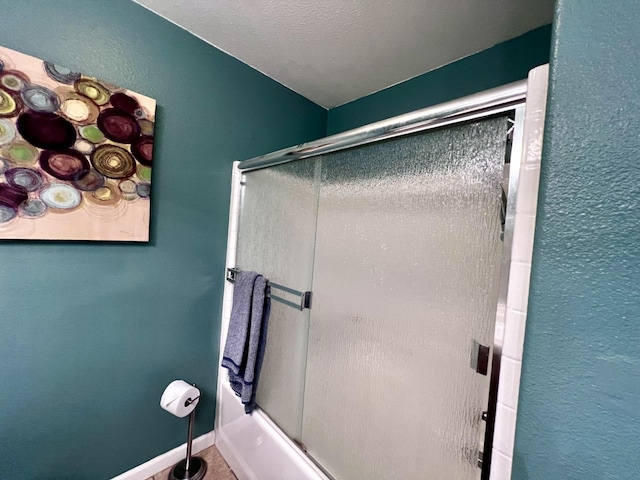 bathroom featuring enclosed tub / shower combo and a textured ceiling