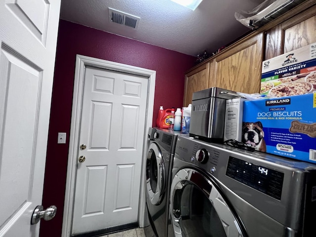 laundry area with cabinets, light tile patterned floors, washer and dryer, and a textured ceiling