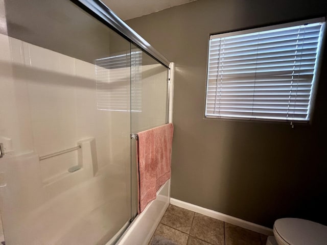 bathroom with tile patterned floors, toilet, and bath / shower combo with glass door