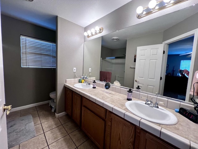 bathroom with tile patterned floors, an enclosed shower, a textured ceiling, vanity, and toilet