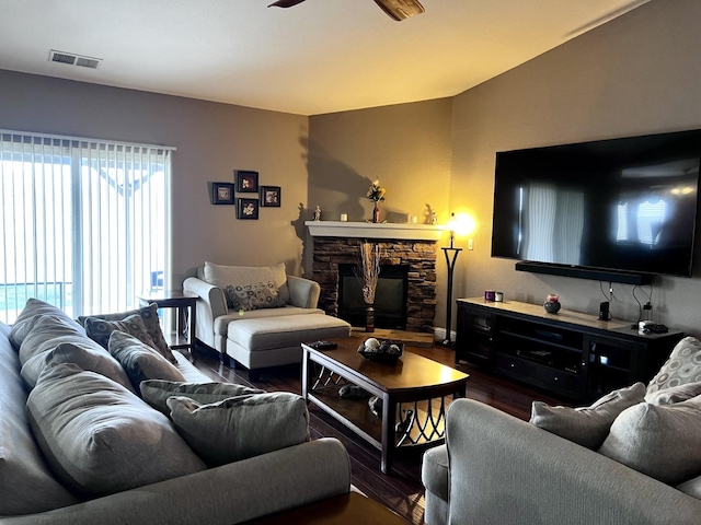 living room featuring hardwood / wood-style flooring, a stone fireplace, and ceiling fan