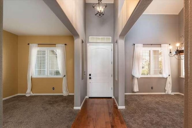 entryway with dark carpet and a notable chandelier