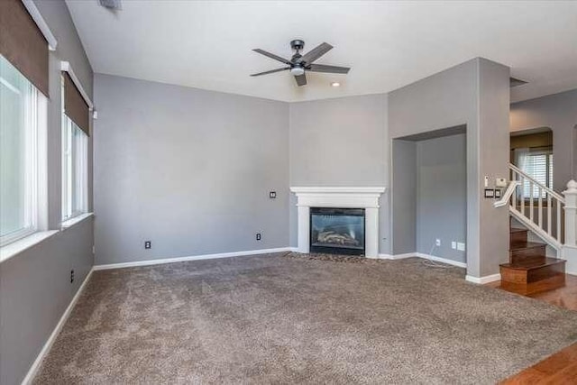 unfurnished living room featuring ceiling fan, plenty of natural light, and carpet flooring