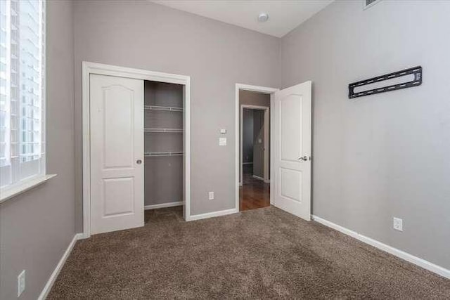 unfurnished bedroom with dark colored carpet and a closet