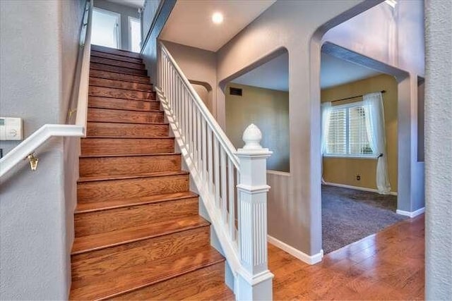 stairs with hardwood / wood-style floors and a wealth of natural light