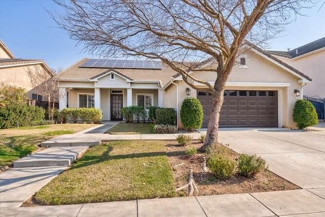 view of front of home featuring a garage, a front yard, and solar panels