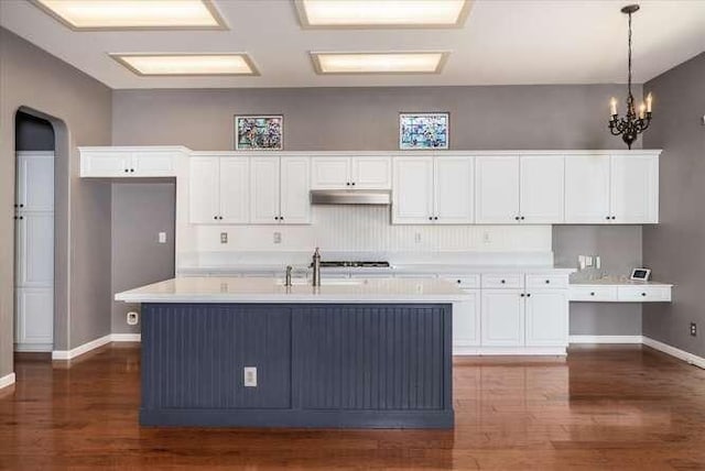 kitchen featuring hanging light fixtures, an island with sink, sink, and white cabinets