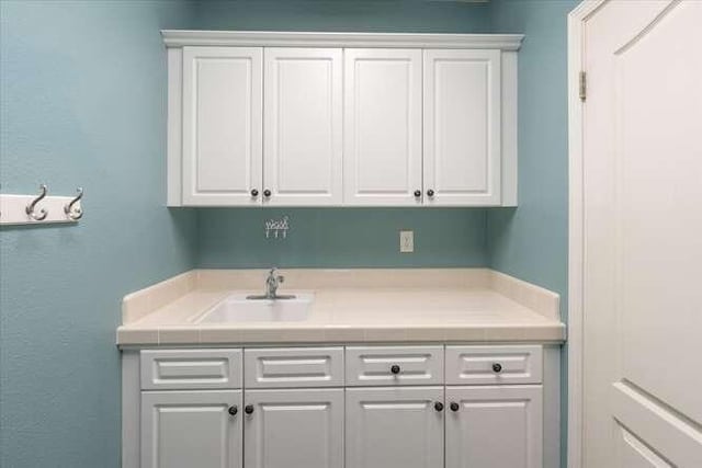 bar with white cabinetry and sink