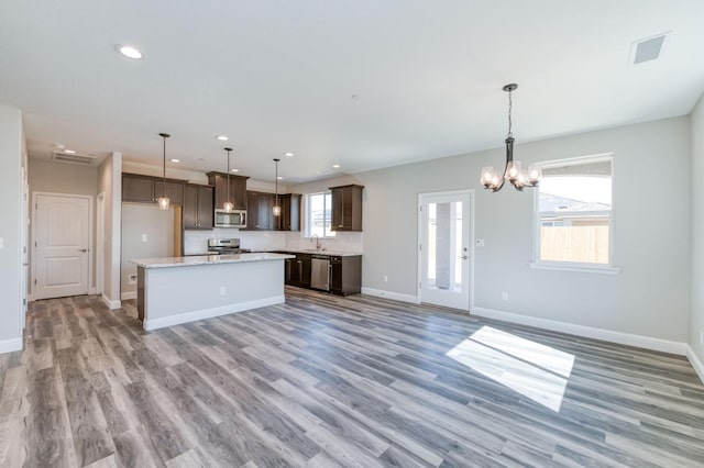 kitchen with light wood-type flooring, stainless steel appliances, and a kitchen island