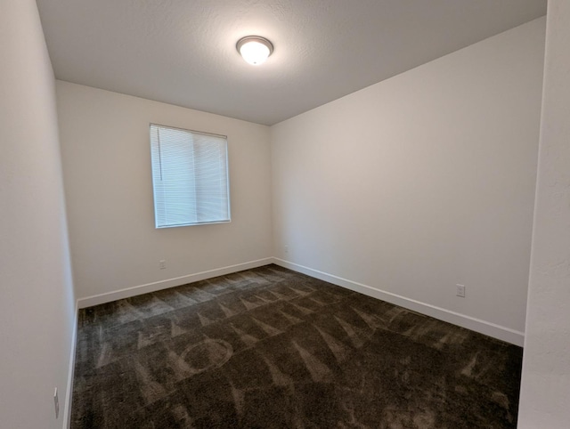 empty room featuring dark carpet and a textured ceiling