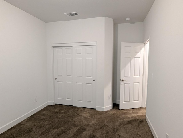 unfurnished bedroom with a closet and dark colored carpet