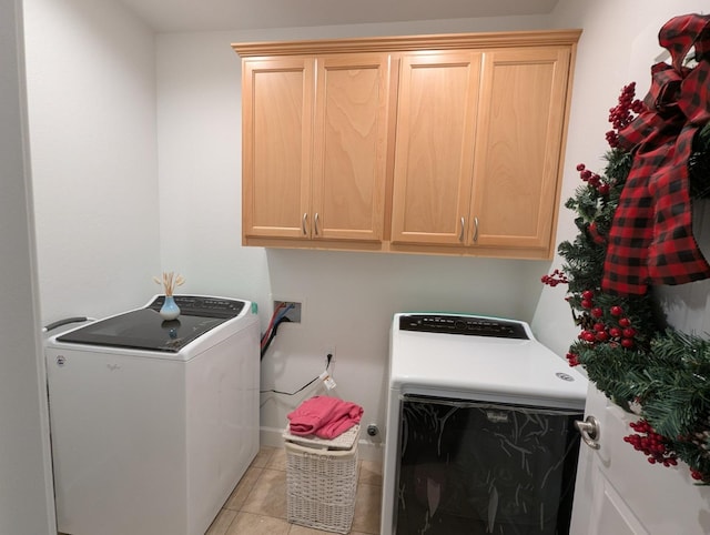 washroom with washing machine and clothes dryer, light tile patterned flooring, and cabinets