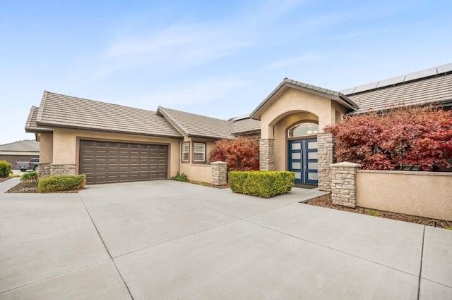 ranch-style house featuring a garage and solar panels