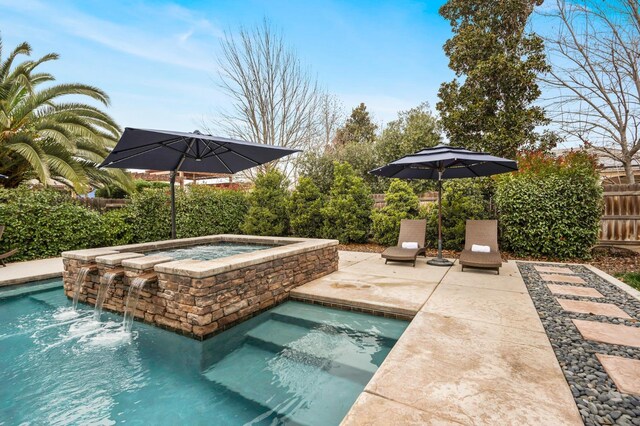 view of pool featuring a patio, pool water feature, and an in ground hot tub