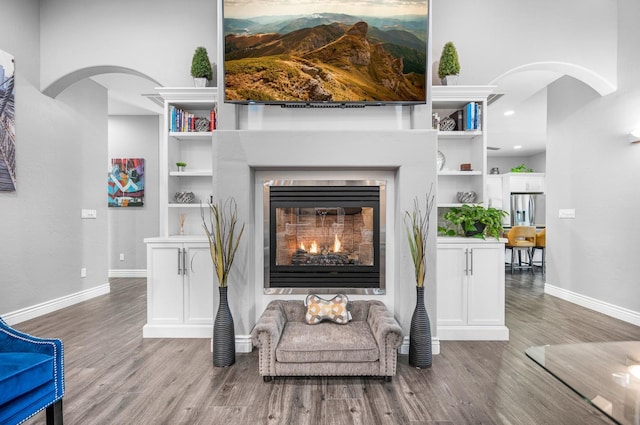 living room featuring built in shelves and wood-type flooring