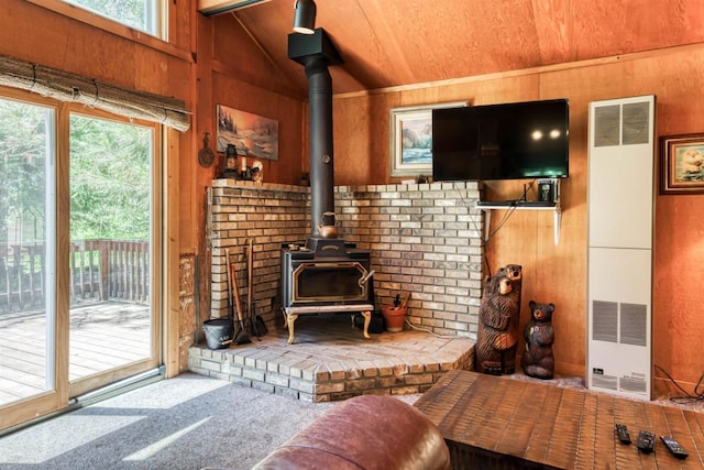 living room featuring a wood stove, wood walls, vaulted ceiling, carpet, and wood ceiling