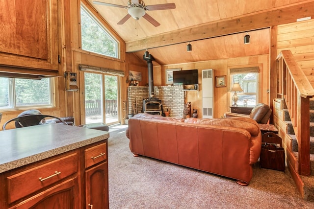 living room featuring a wood stove, lofted ceiling with beams, wood walls, light carpet, and wood ceiling