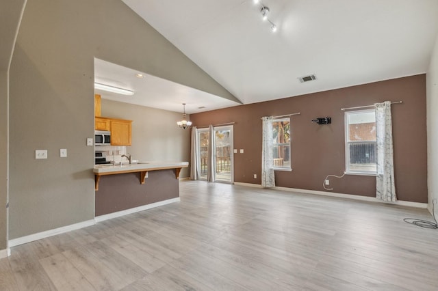 unfurnished living room with light hardwood / wood-style floors, sink, high vaulted ceiling, and an inviting chandelier