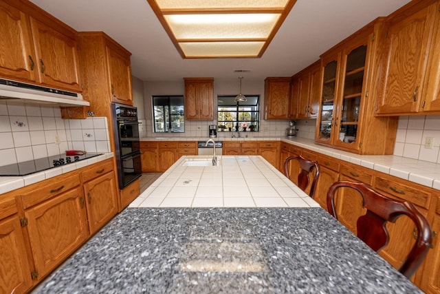 kitchen featuring sink, tile countertops, backsplash, and black appliances