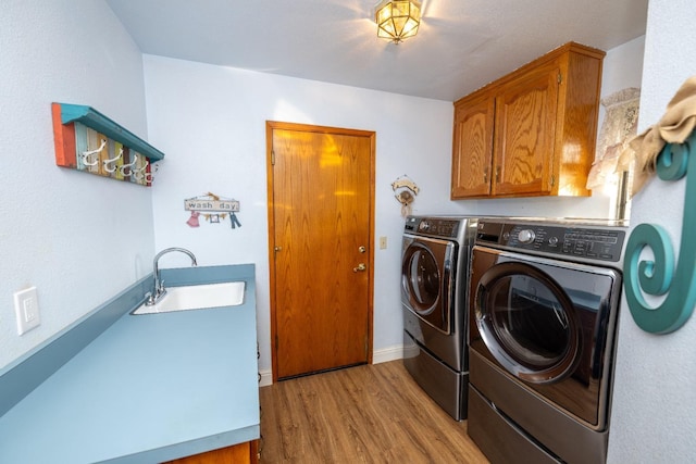 washroom featuring cabinets, light wood-type flooring, washing machine and dryer, and sink