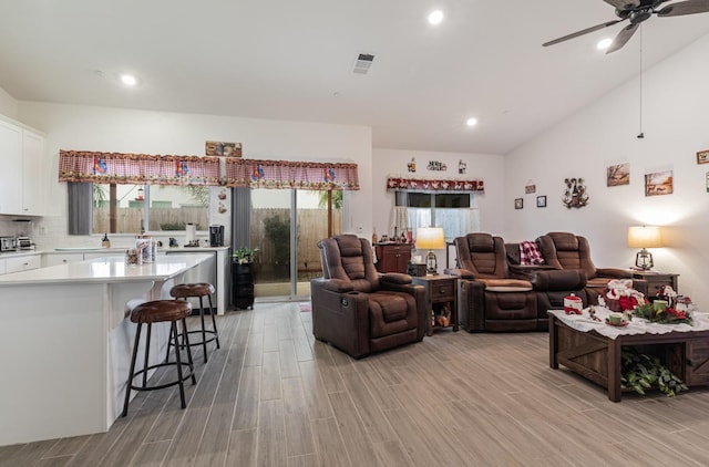 living room featuring ceiling fan, lofted ceiling, and light hardwood / wood-style flooring