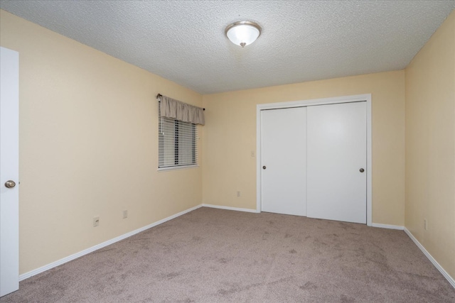 unfurnished bedroom featuring carpet floors, a textured ceiling, baseboards, and a closet