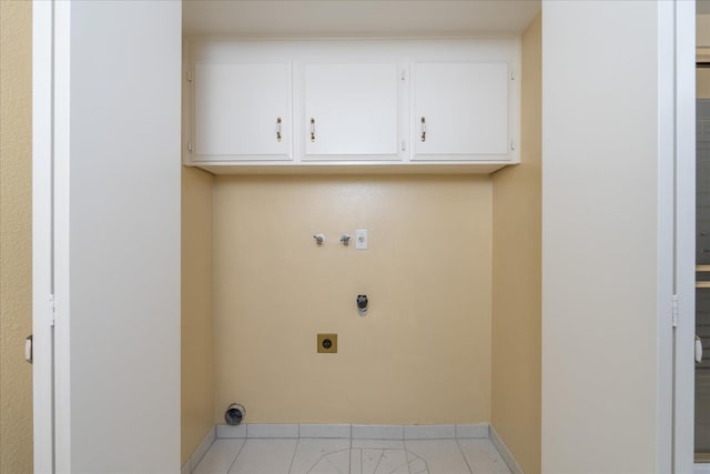 clothes washing area featuring light tile patterned floors, hookup for a gas dryer, cabinet space, electric dryer hookup, and baseboards