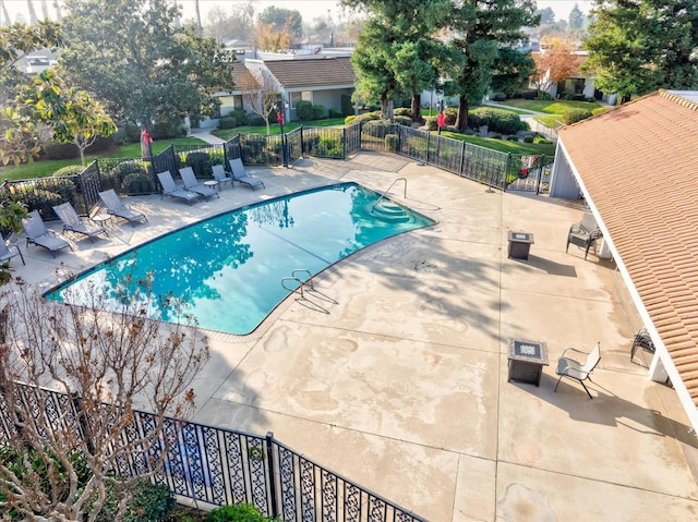 community pool with a patio area and fence