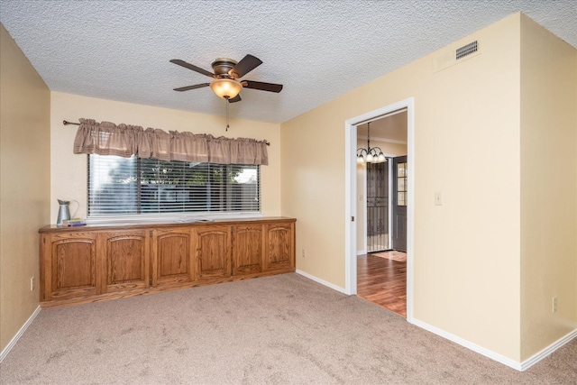 spare room featuring ceiling fan, a textured ceiling, visible vents, and light colored carpet