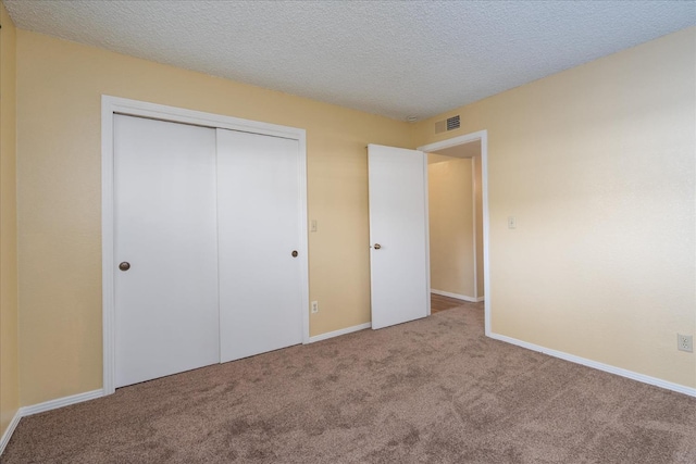 unfurnished bedroom with carpet floors, a closet, visible vents, and a textured ceiling