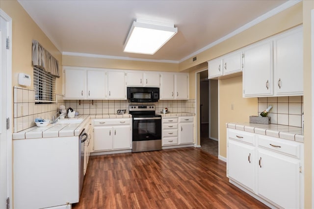 kitchen with electric stove, dark wood-style flooring, tile countertops, white cabinets, and black microwave