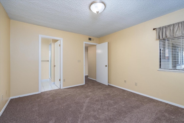 unfurnished bedroom with baseboards, a textured ceiling, visible vents, and carpet flooring