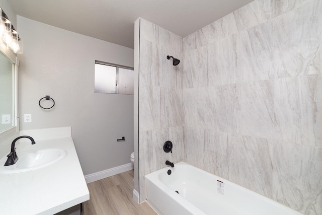 full bathroom featuring toilet, shower / bath combination, wood finished floors, vanity, and baseboards